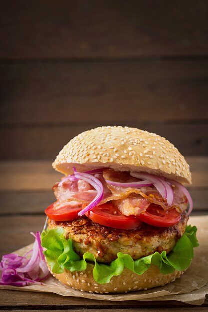 Sándwich grande - hamburguesa con carne de res, cebolla roja, tomate y tocino frito.