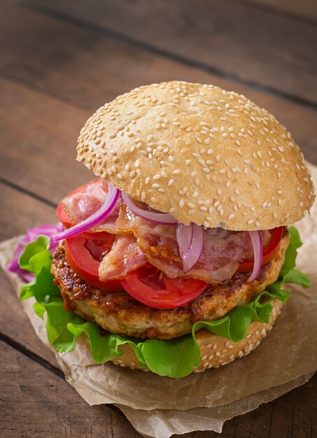 Sándwich grande - hamburguesa con carne de res, cebolla roja, tomate y tocino frito.