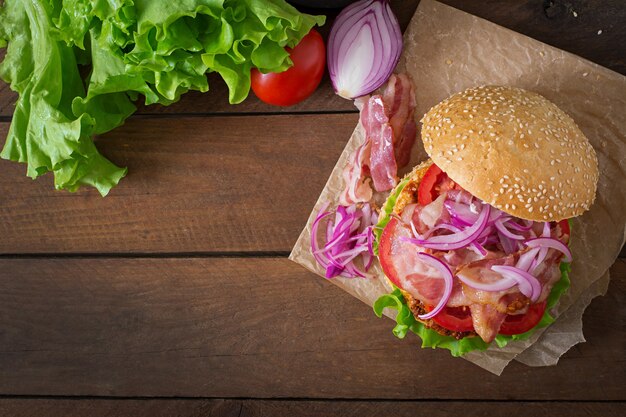 Sándwich grande - hamburguesa con carne de res, cebolla roja, tomate y tocino frito.