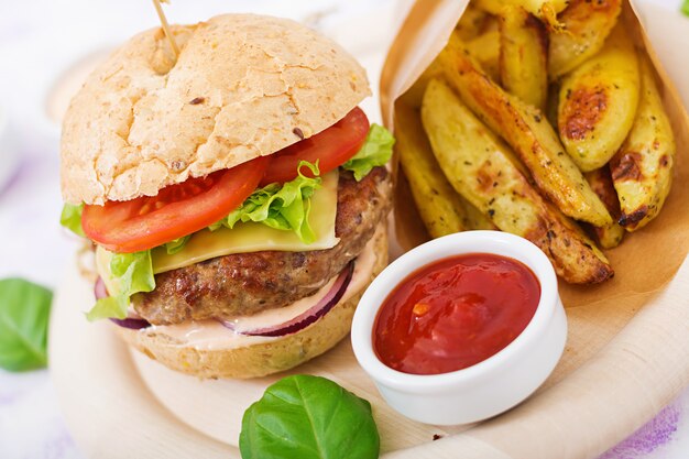 Sándwich grande: hamburguesa con jugosa hamburguesa de ternera, queso, tomate, cebolla roja y papas fritas.