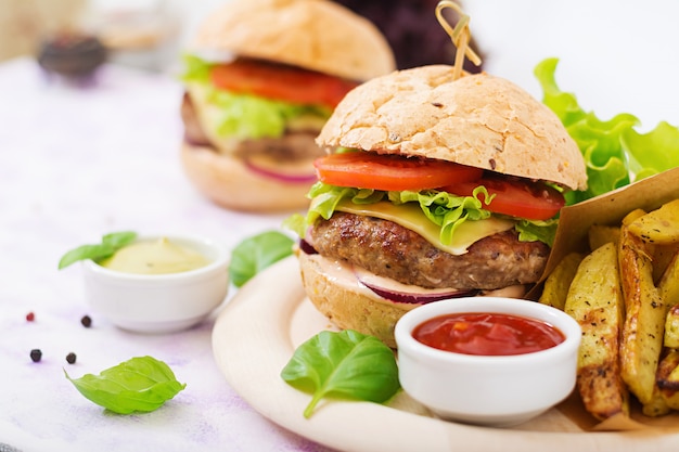 Sándwich grande: hamburguesa con jugosa hamburguesa de ternera, queso, tomate, cebolla roja y papas fritas.