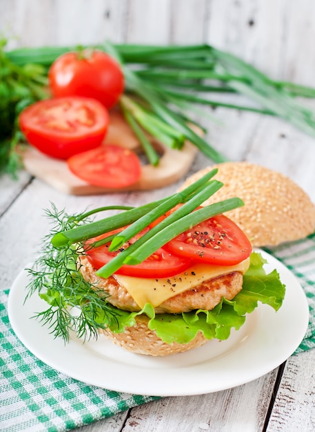 Sandwich con hamburguesa de pollo, tomate, queso y lechuga.