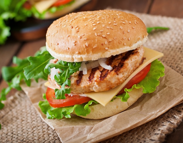 Sandwich con hamburguesa de pollo, tomate, queso y lechuga.