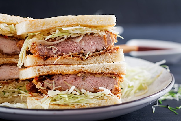 Foto gratuita sándwich japonés con chuleta de cerdo empanada, col y salsa tonkatsu.