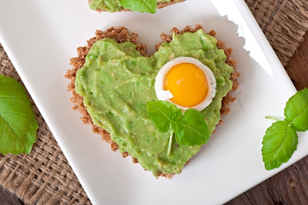 Sandwich con pasta de aguacate y huevo en forma de corazón