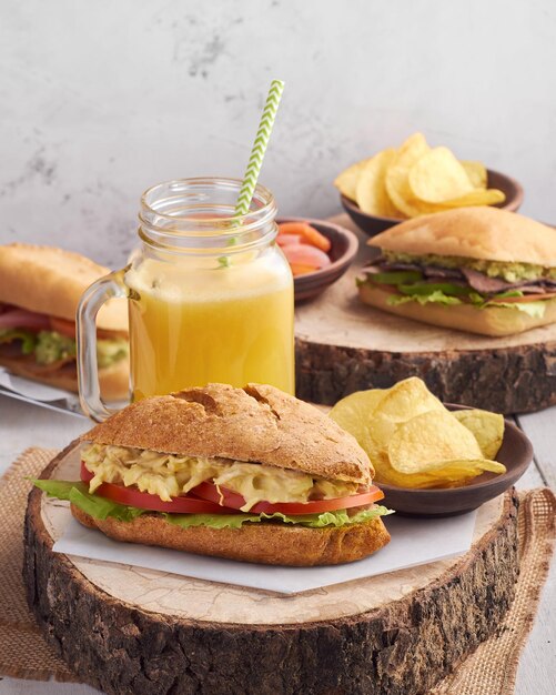 Sándwich de pollo en mayonesa y salsa de yogur servido con jugo de naranja y papas fritas