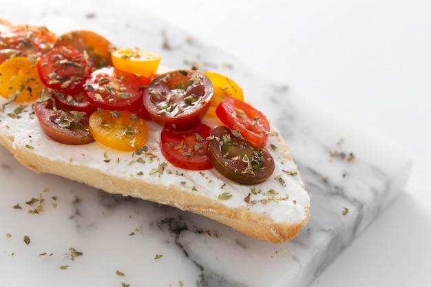 Sándwich con queso crema y tomates en mostrador de mármol