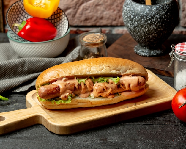 Sandwich de salchichas con salsa picante y lechuga