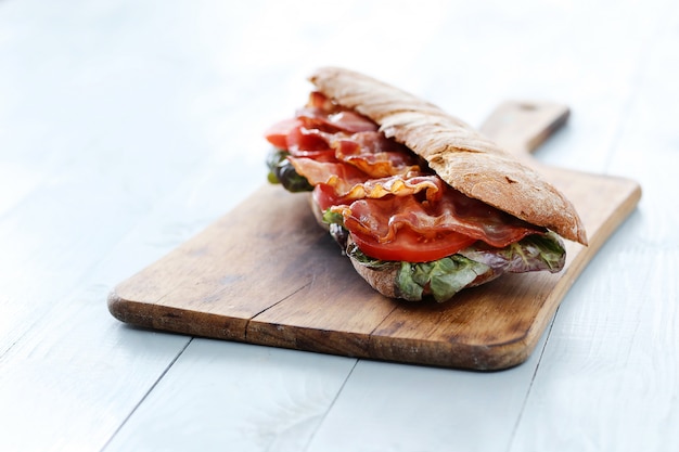 Sandwich de tocino en tabla de cortar de madera