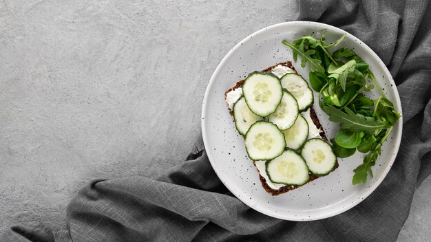 Sándwich de vista superior con pepinos en plato con paño de cocina