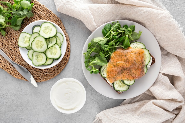 Foto gratuita sándwich de vista superior con pepinos y salmón en un plato con espinacas