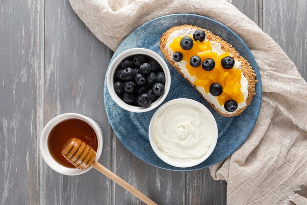Sándwich de vista superior con queso crema y frutas en un plato con miel