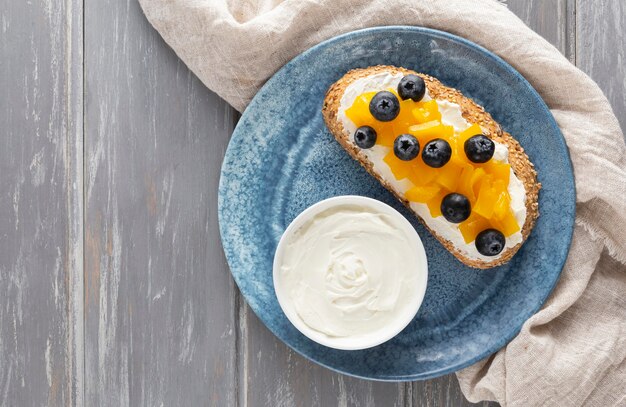 Sándwich de vista superior con queso crema y frutas en un plato