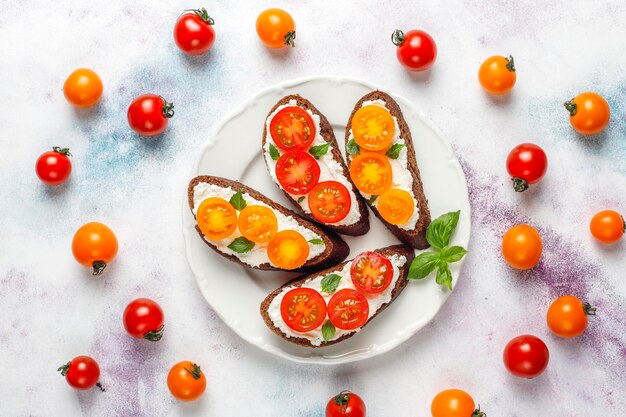 Sándwiches abiertos con requesón, tomates cherry y albahaca.