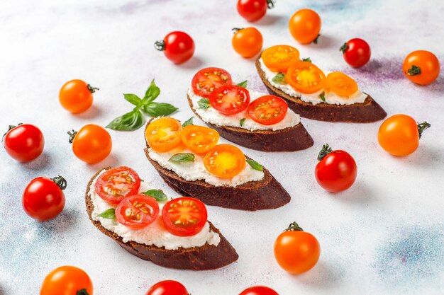 Sándwiches abiertos con requesón, tomates cherry y albahaca.