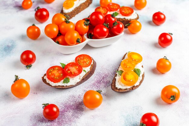 Sándwiches abiertos con requesón, tomates cherry y albahaca.