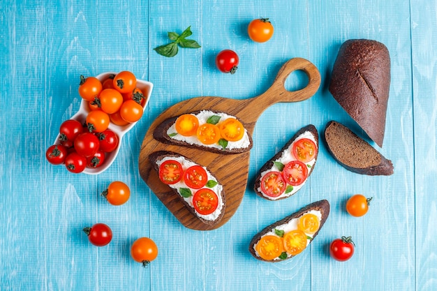 Sándwiches abiertos con requesón, tomates cherry y albahaca.