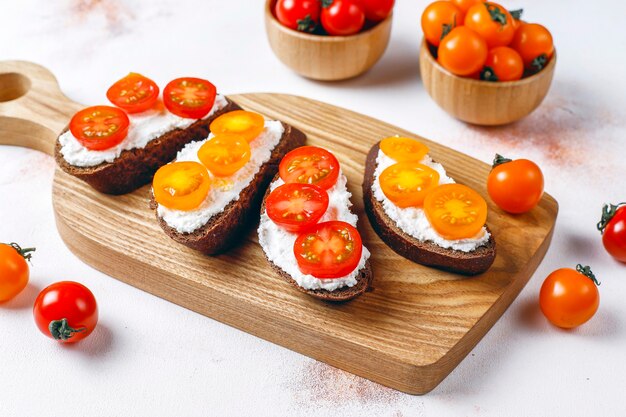 Sándwiches abiertos con requesón, tomates cherry y albahaca.