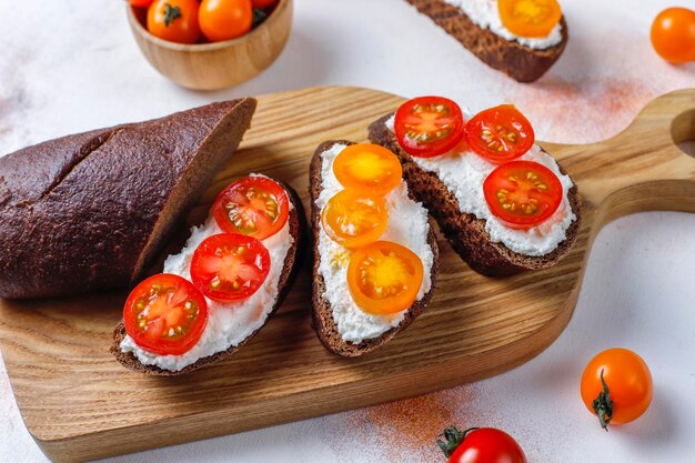 Sándwiches abiertos con requesón, tomates cherry y albahaca.