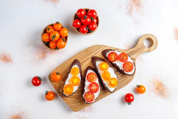 Sándwiches abiertos con requesón, tomates cherry y albahaca.