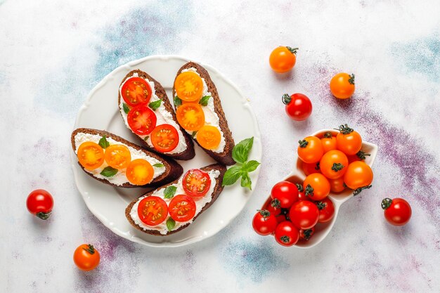 Sándwiches abiertos con requesón, tomates cherry y albahaca.