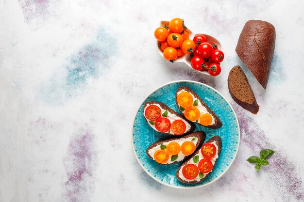 Sándwiches abiertos con requesón, tomates cherry y albahaca.