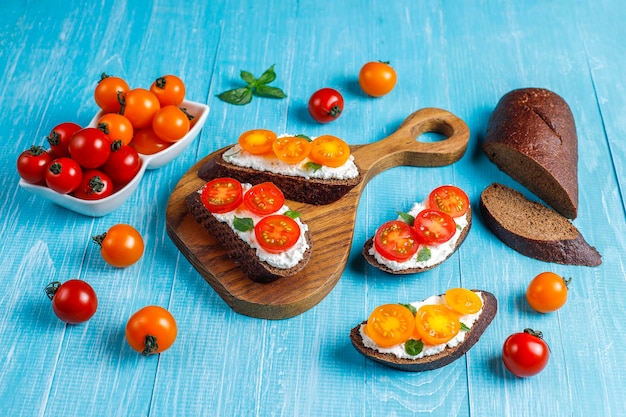 Sándwiches abiertos con requesón, tomates cherry y albahaca.