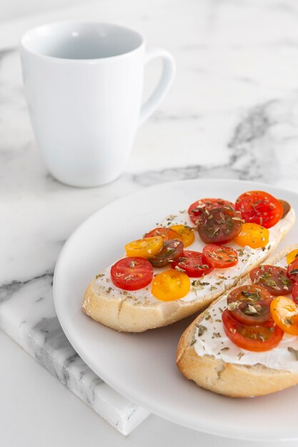 Sándwiches de alto ángulo con queso crema y tomates con taza