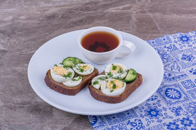 Sándwiches con huevos duros y hierbas con una taza de té.