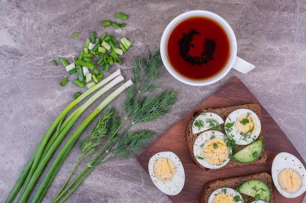 Sándwiches con huevos duros y hierbas con una taza de té.