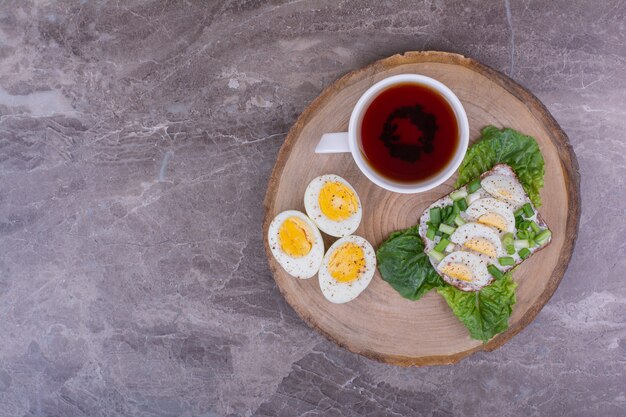 Sándwiches con huevos duros y hierbas con una taza de té.