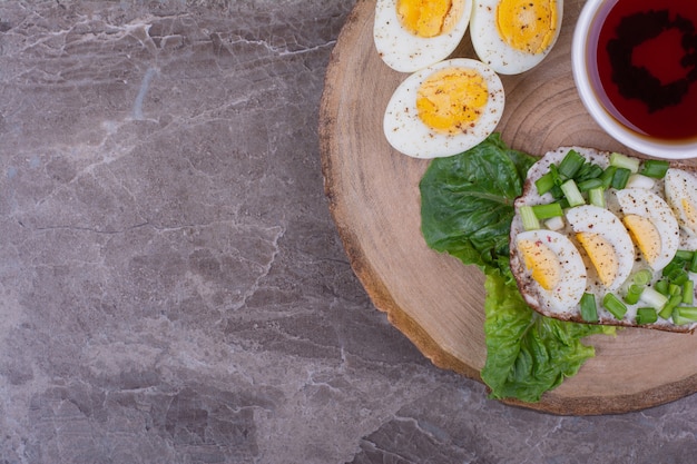 Sándwiches con huevos duros y hierbas con una taza de té.