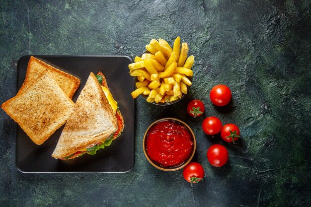 Sándwiches de jamón de vista superior con tomates rojos frescos y pasta de tomate en una superficie oscura