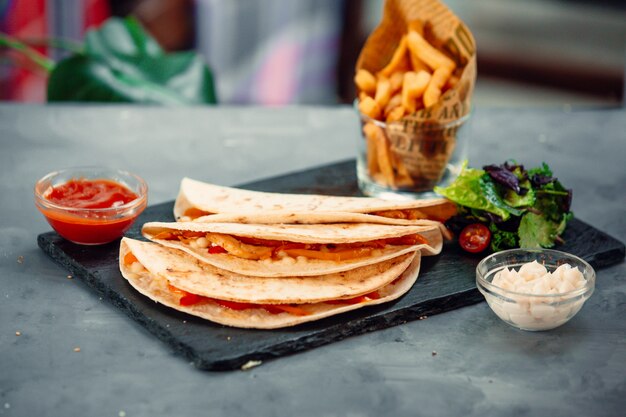 Sandwiches en lavash con salsa de tomate, ensalada verde y papas fritas.