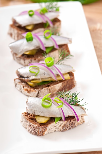 Sandwiches de pan de centeno con arenque, cebolla y hierbas.