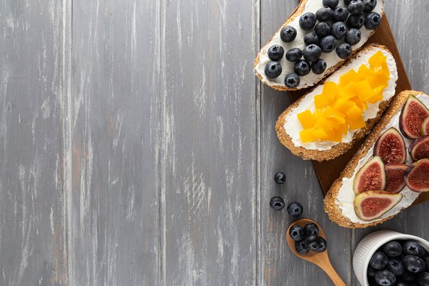 Sándwiches planos con queso crema y frutas con espacio de copia