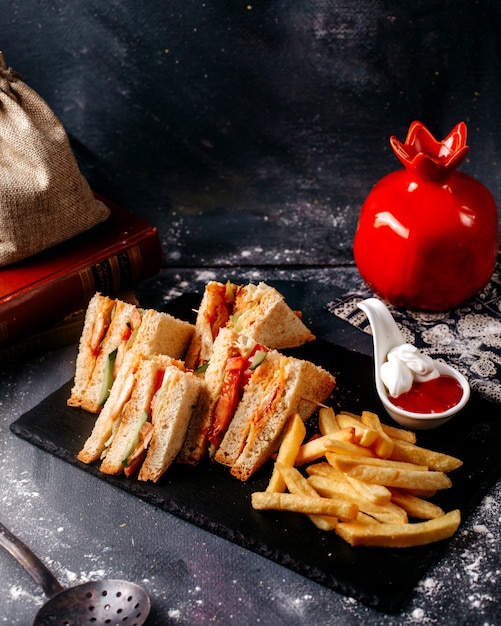 Sándwiches de vista frontal junto con papas fritas en la superficie gris