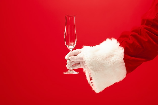 Santa celebración copa de champán sobre fondo rojo. temporada, invierno, vacaciones, celebración, concepto de regalo