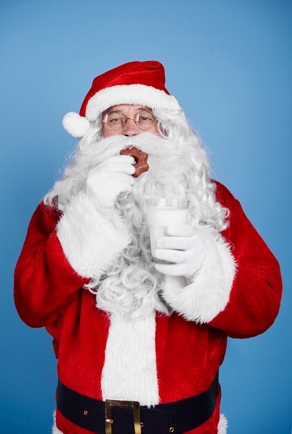 Santa claus hambriento comiendo galletas en foto de estudio