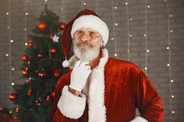 Santa Claus de pie junto al árbol de Navidad. Decoración hogareña.
