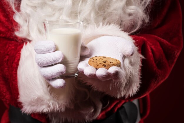 Santa Claus sosteniendo una galleta y un vaso de leche