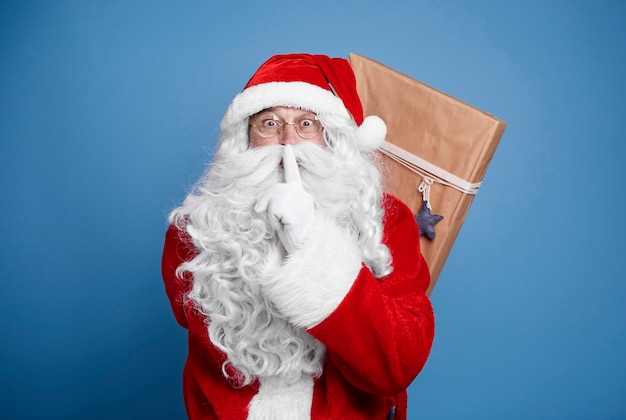 Santa claus sosteniendo regalos de Navidad a sus espaldas