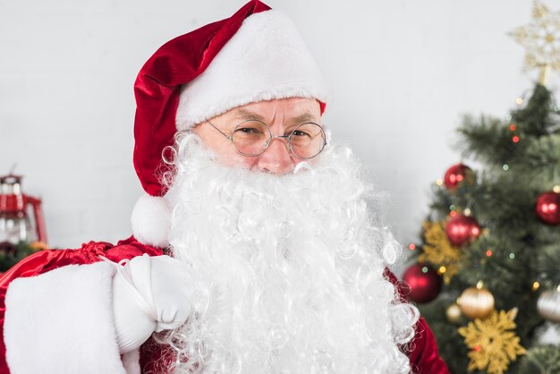 Santa en copas cerca de arbol de navidad