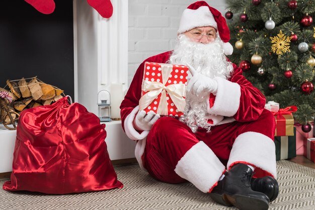 Santa sentado con cajas de regalo en el piso