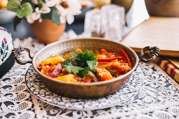 Sartén de cobre con pimientos salteados y pollo con hierbas.