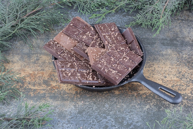 Una sartén oscura llena de chocolates en rodajas sobre fondo de mármol. Foto de alta calidad