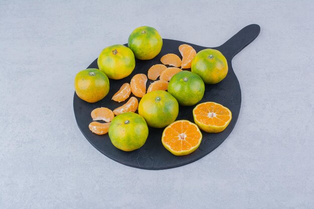 Una sartén oscura de mandarinas amargas sobre fondo blanco. Foto de alta calidad
