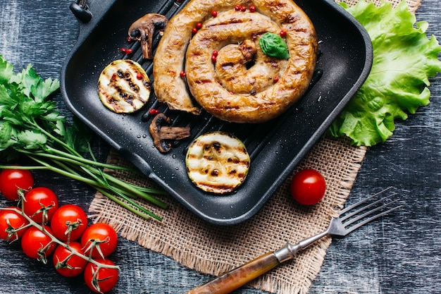 Foto gratuita sartén a la parrilla con deliciosas salchichas a la parrilla en espiral y vegetales.