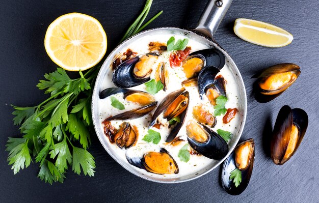 Sartén plana con mejillones en salsa blanca.