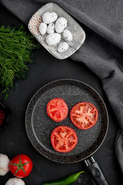 sartén de tomates con huevos e hinojo en mesa negra